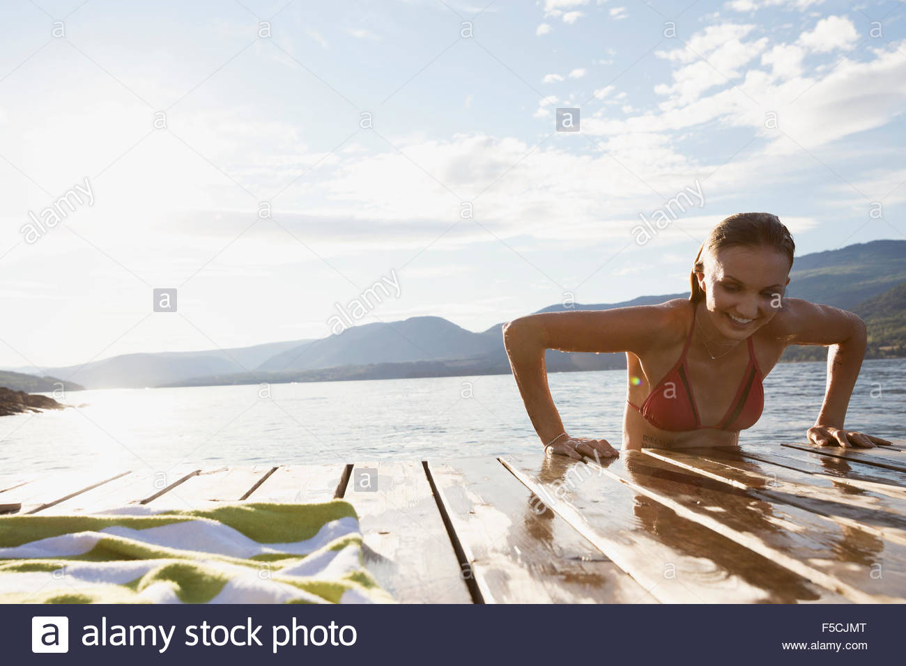 Mujer joven de subirse a lago dock Foto de stock