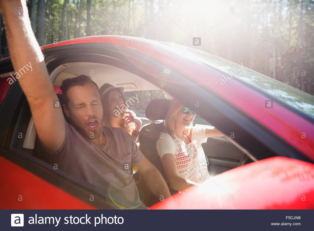 Amigos entusiastas cantando y aclamando en coche Foto de stock