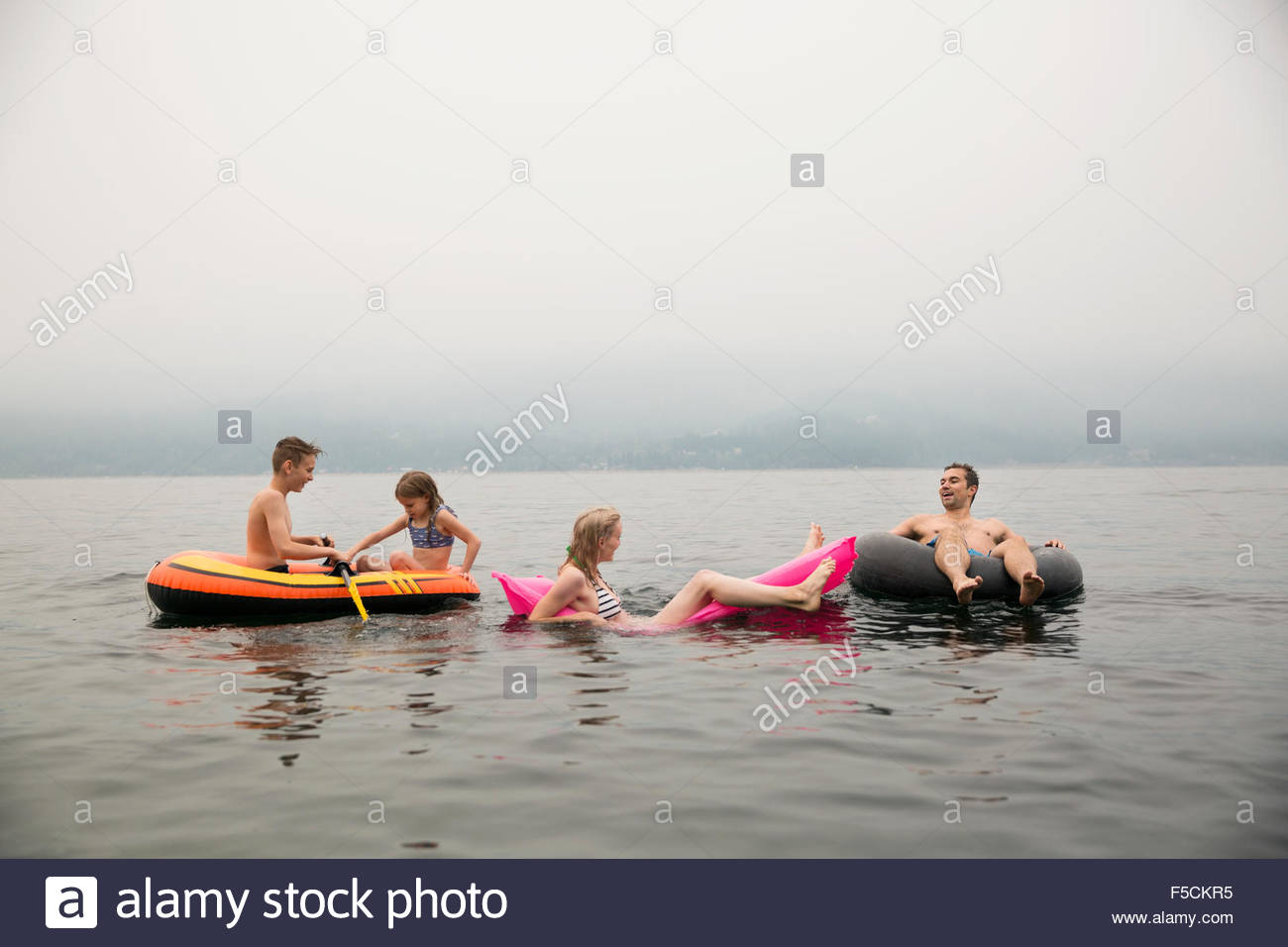 Relajarse en la piscina de la familia balsas en el lago Foto de stock