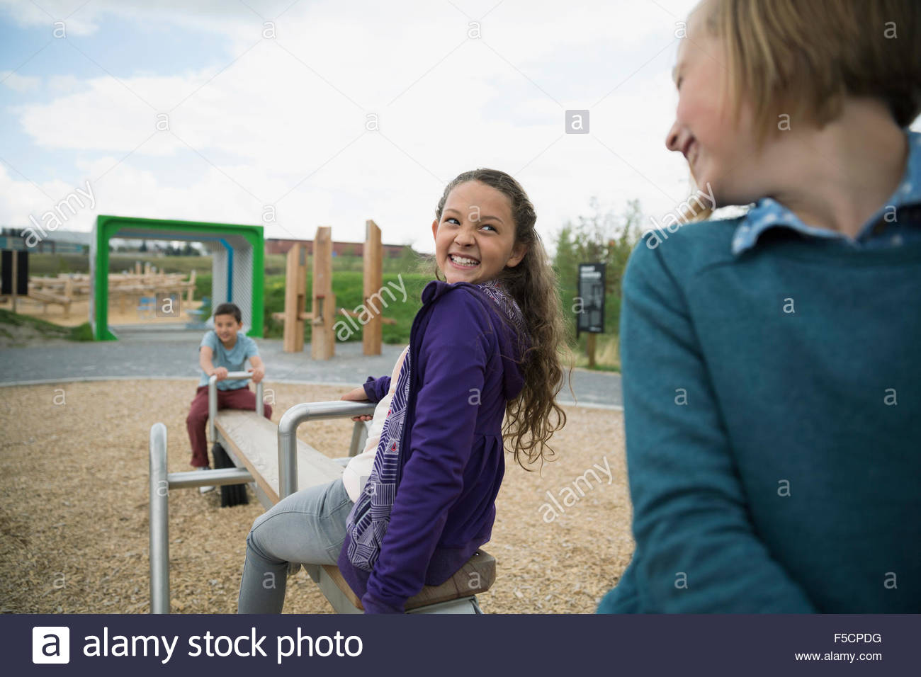 Entusiasta de las niñas jugando en balancín en playground Foto de stock