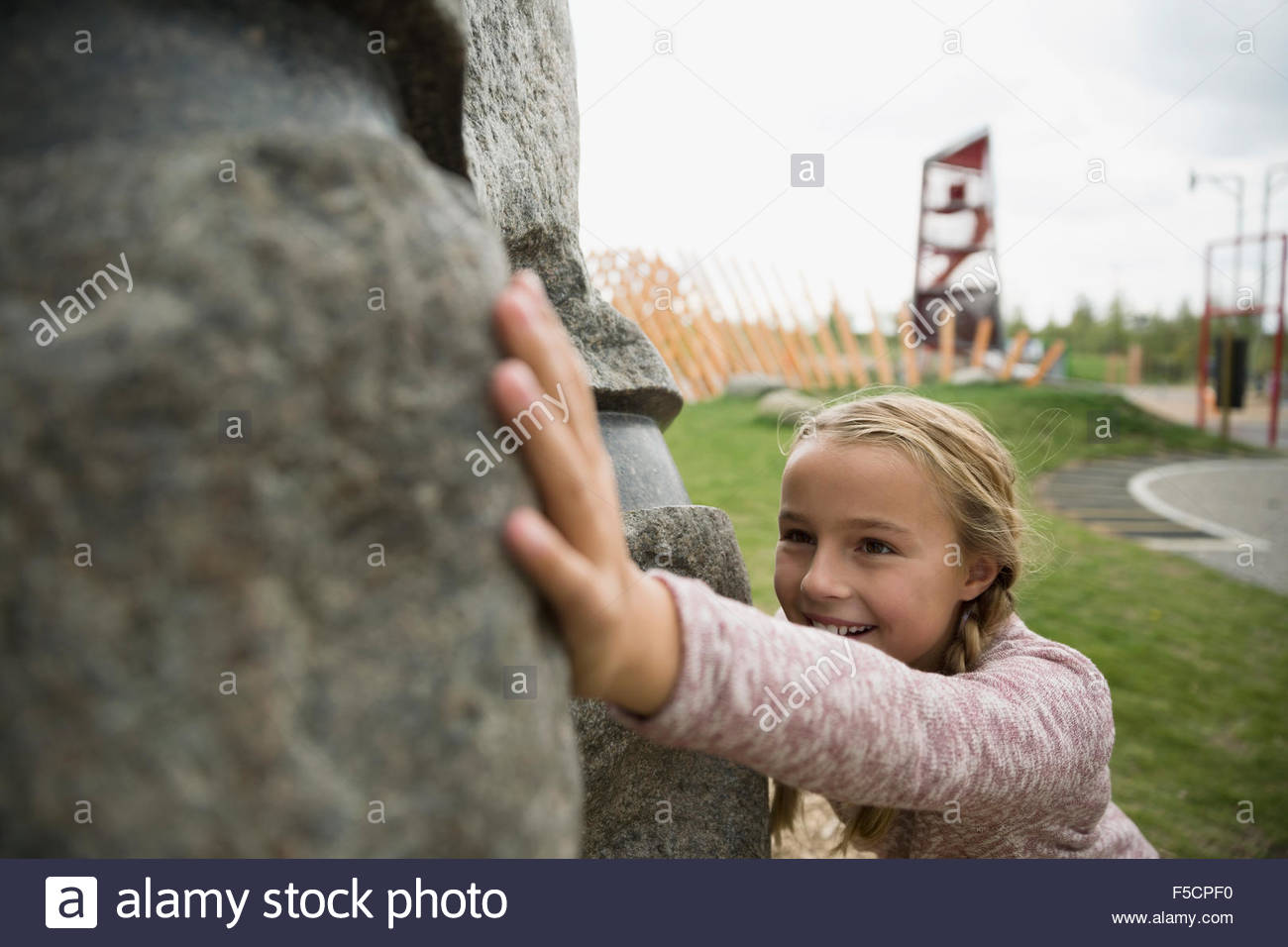 Chica empujando a gran roca en playground Foto de stock