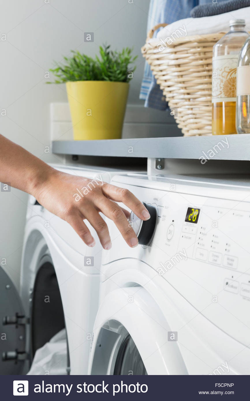 Mujer lavadora girando el dial en lavadero Foto de stock