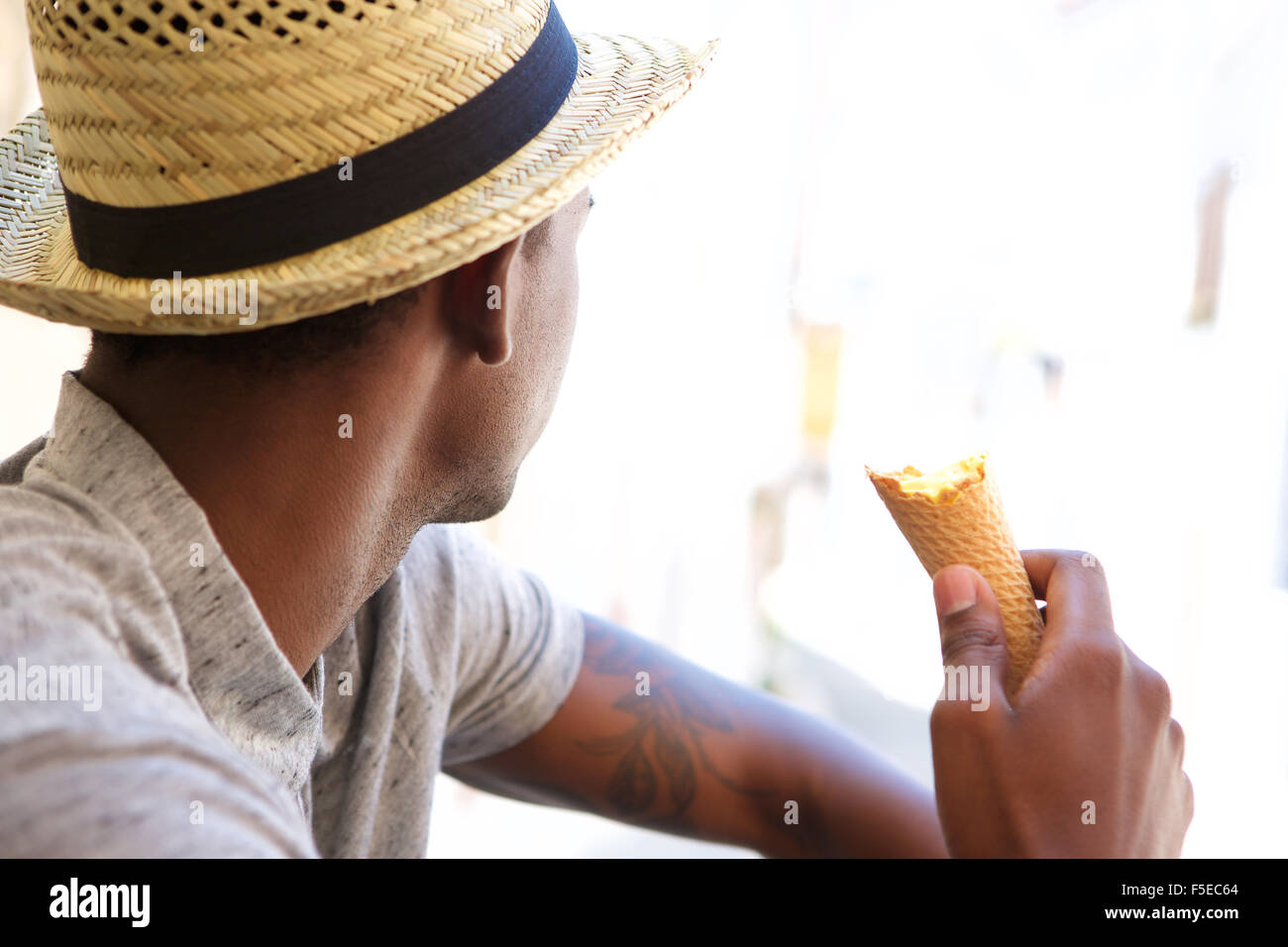 Retrato de un hombre joven con sombrero comer helado y mirar lejos  Fotografía de stock - Alamy