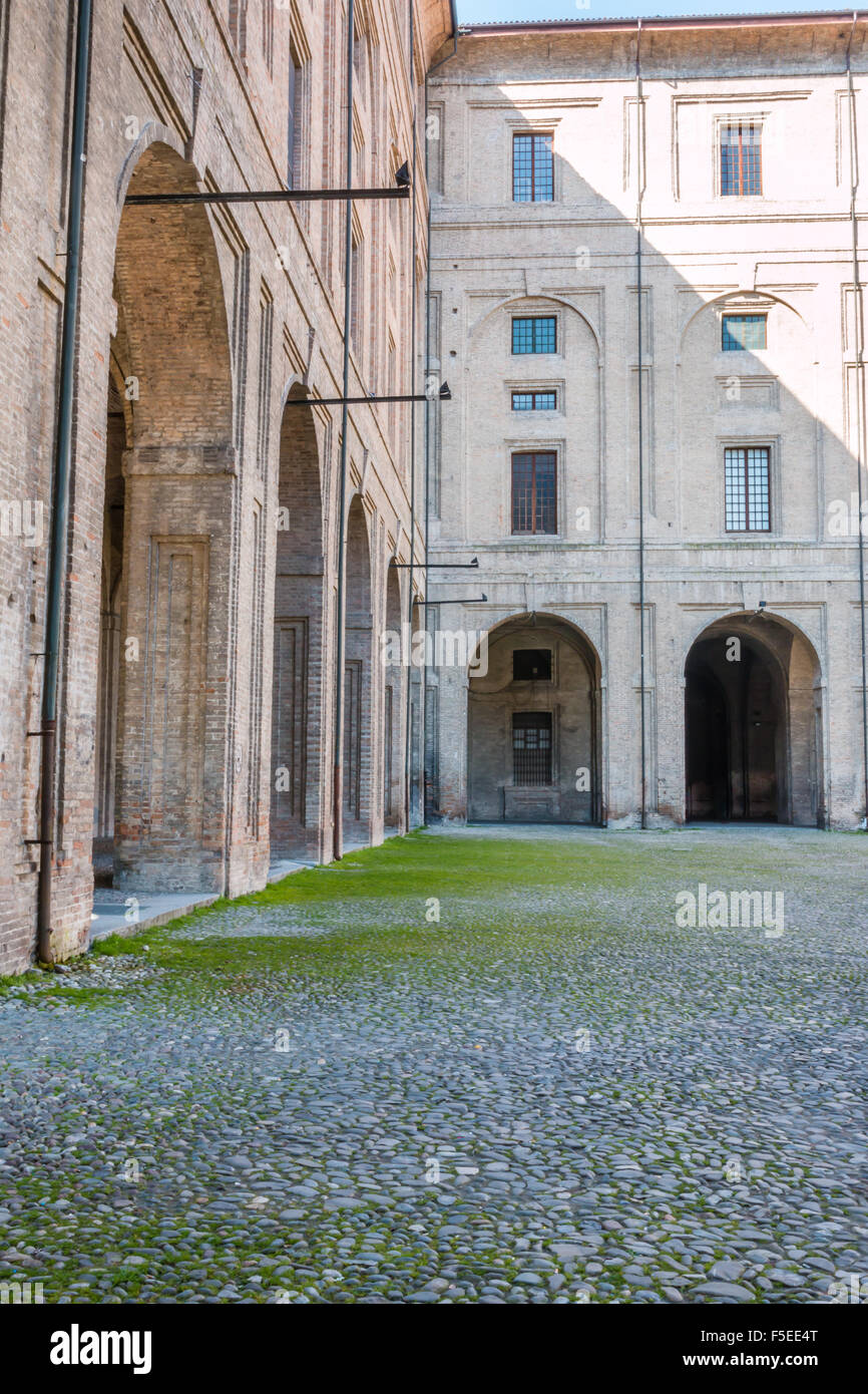 Arco, columnas, el patio y los adoquines en el Palacio de La Pilotta, Parma - Italia Foto de stock