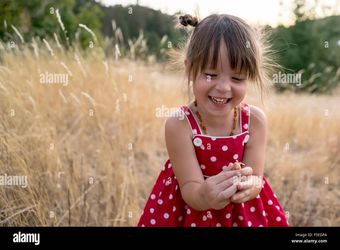 Laughing chica sentada en un campo Foto de stock