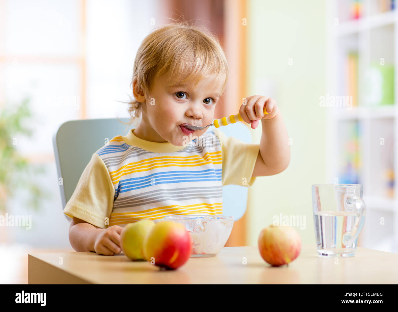 Niño comer alimentos saludables con la mano izquierda en casa Foto de stock