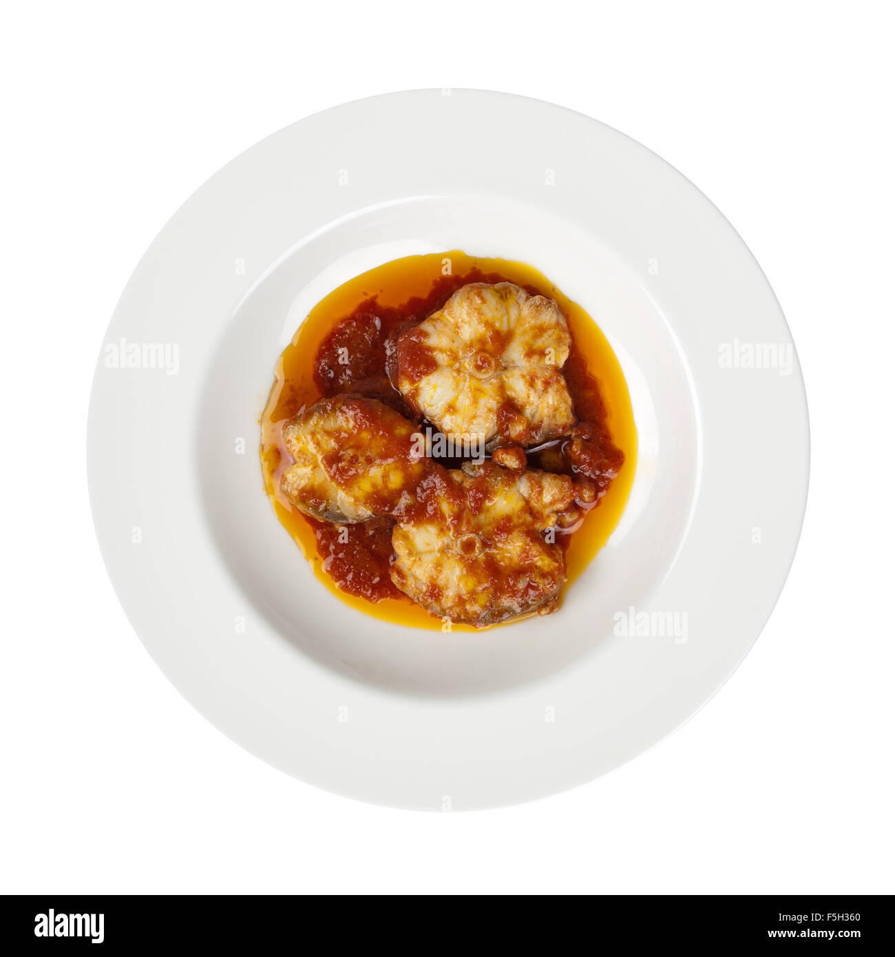 Rodajas de pescado, tomate, aceite de oliva y ajo en la placa redonda, marisco italiana receta tradicional conocido como Palombo alla Livornese Foto de stock