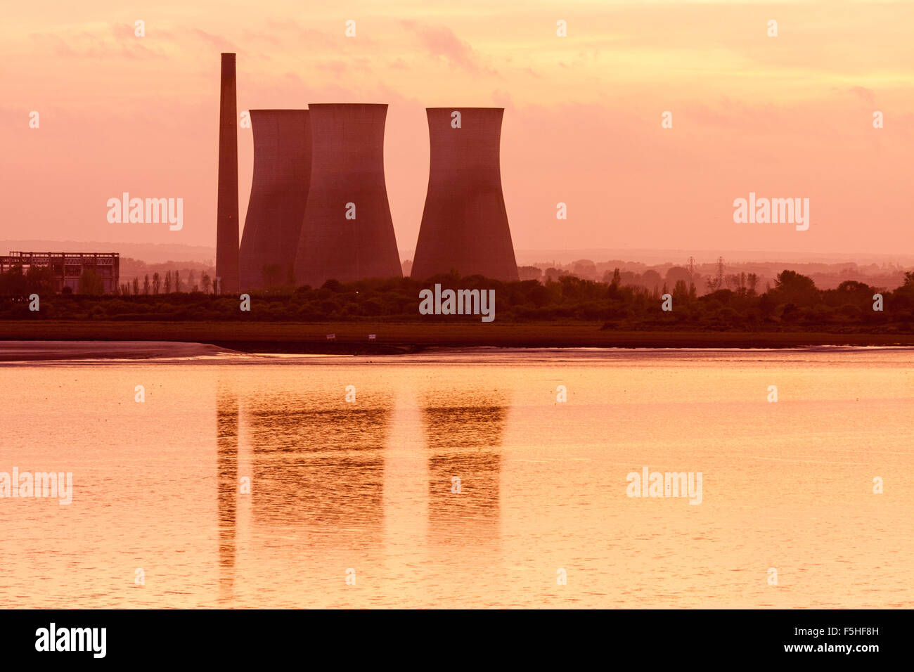 Teleobjetivo Richborough power station con tres torres de refrigeración durante la puesta de sol, sundown, torres de luz reflejada en el mar tranquilo de Pegwell Bay. Foto de stock
