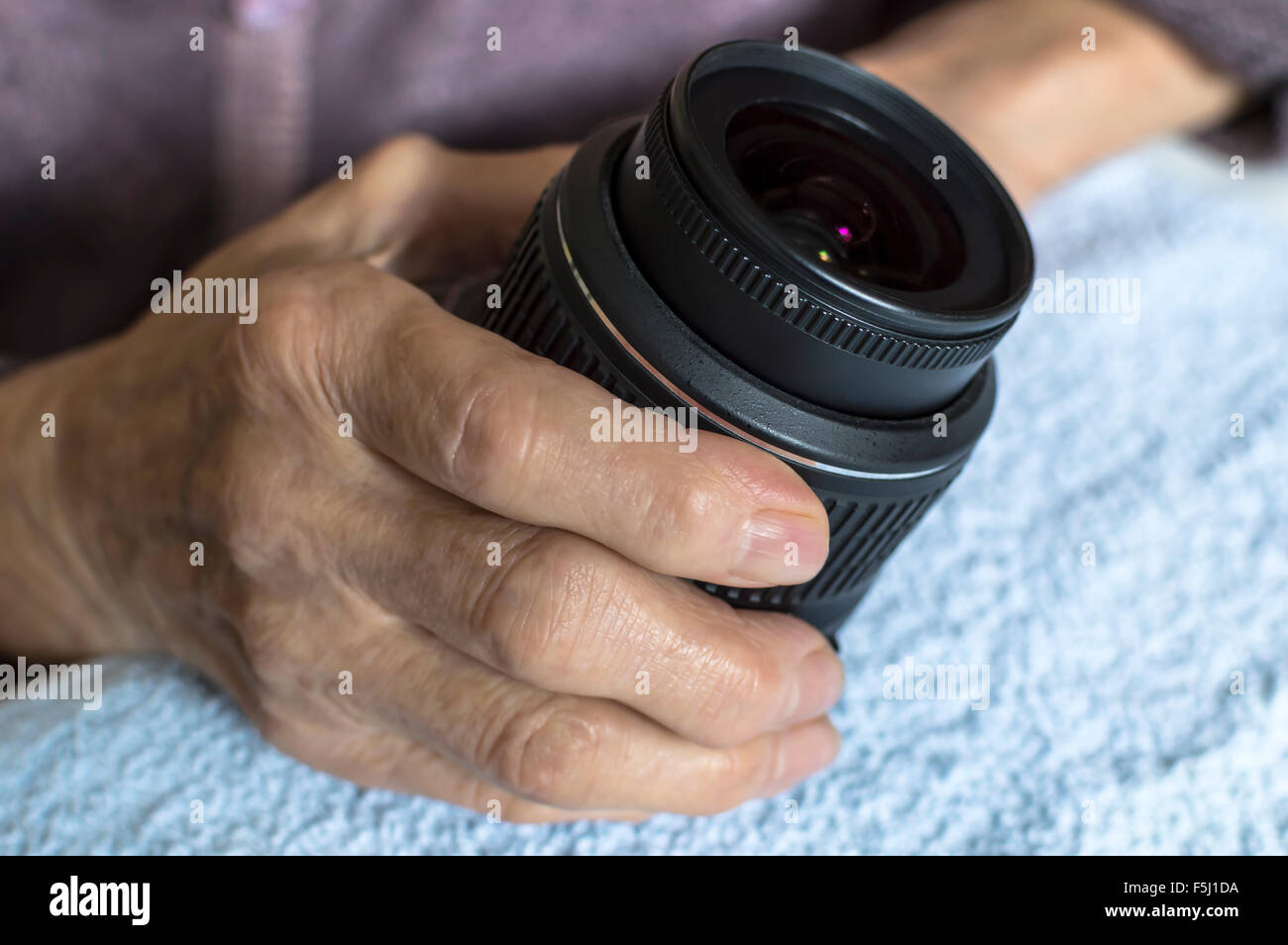 Lente DSLR en las manos de una anciana. El enfoque selectivo. Foto de stock