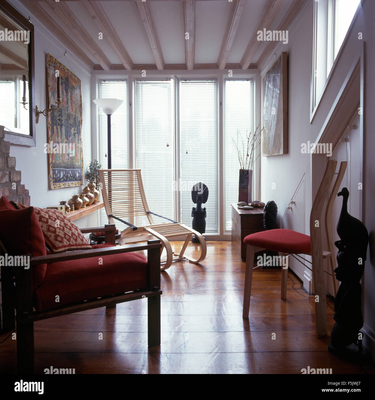Piso de madera pulida en una casa blanca salón con muebles de madera clara y ventanas del suelo al techo. Foto de stock