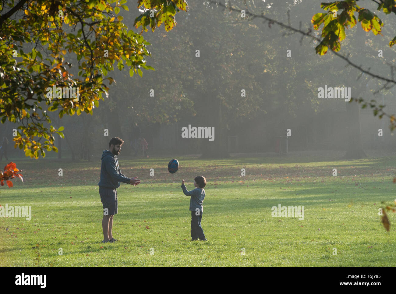 Un padre y su hijo juegan rugby juntos en un parque Foto de stock