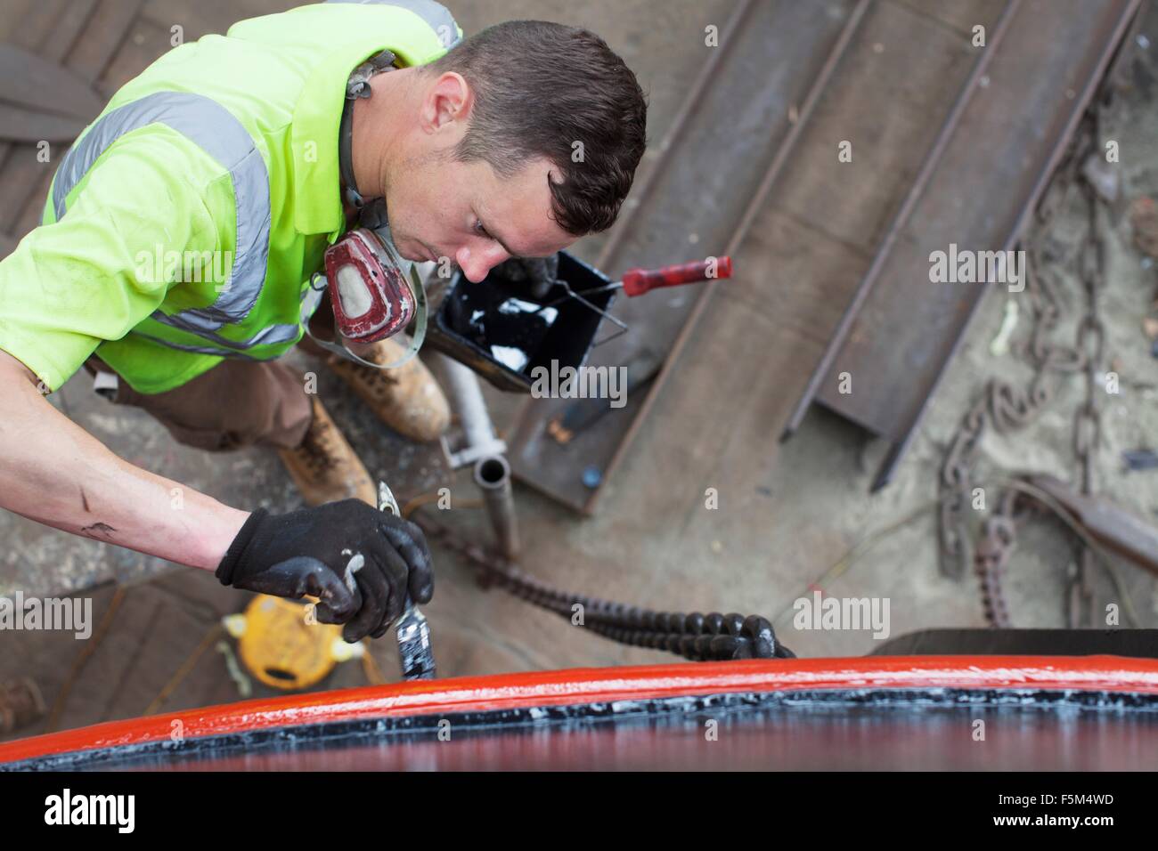 Un alto ángulo de visualización del trabajador del lado de pintura de barco en el astillero Foto de stock