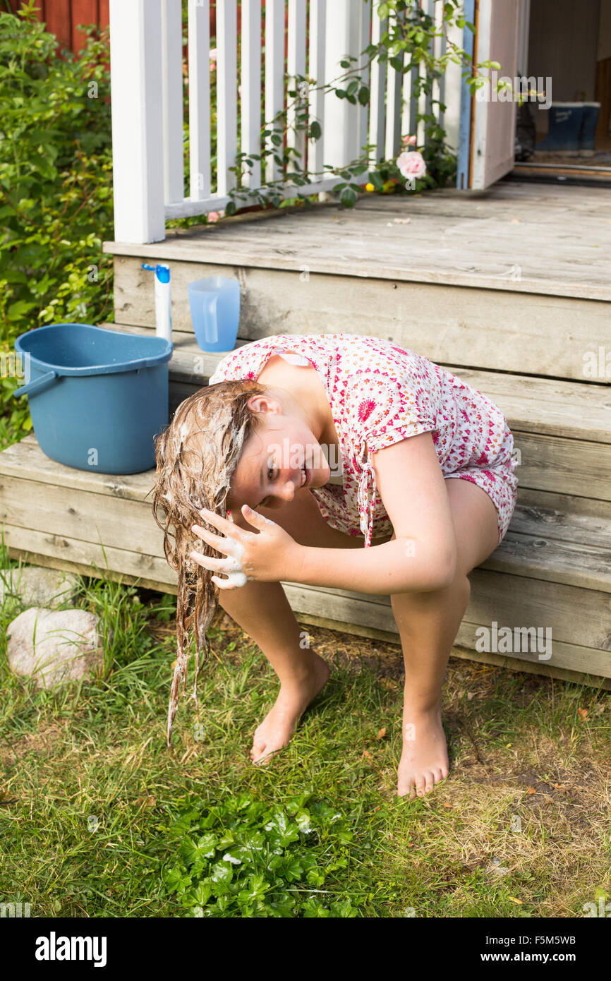 Suecia, archipiélago de Estocolmo, Grasko, Girl (12-13) lavando el cabello fuera Foto de stock