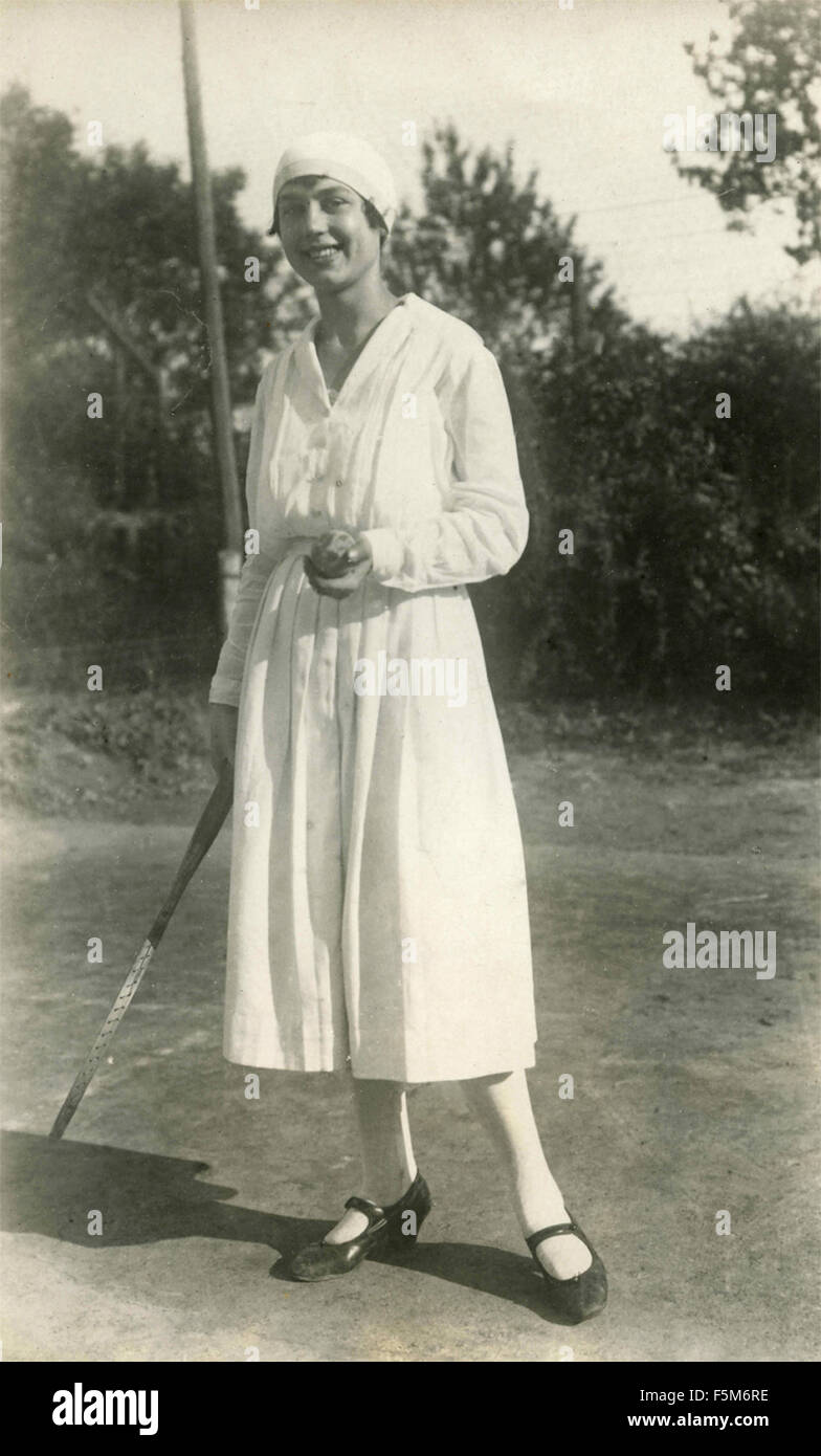 Una mujer con sombrero y vestido blanco jugando al tenis, Italia Foto de stock
