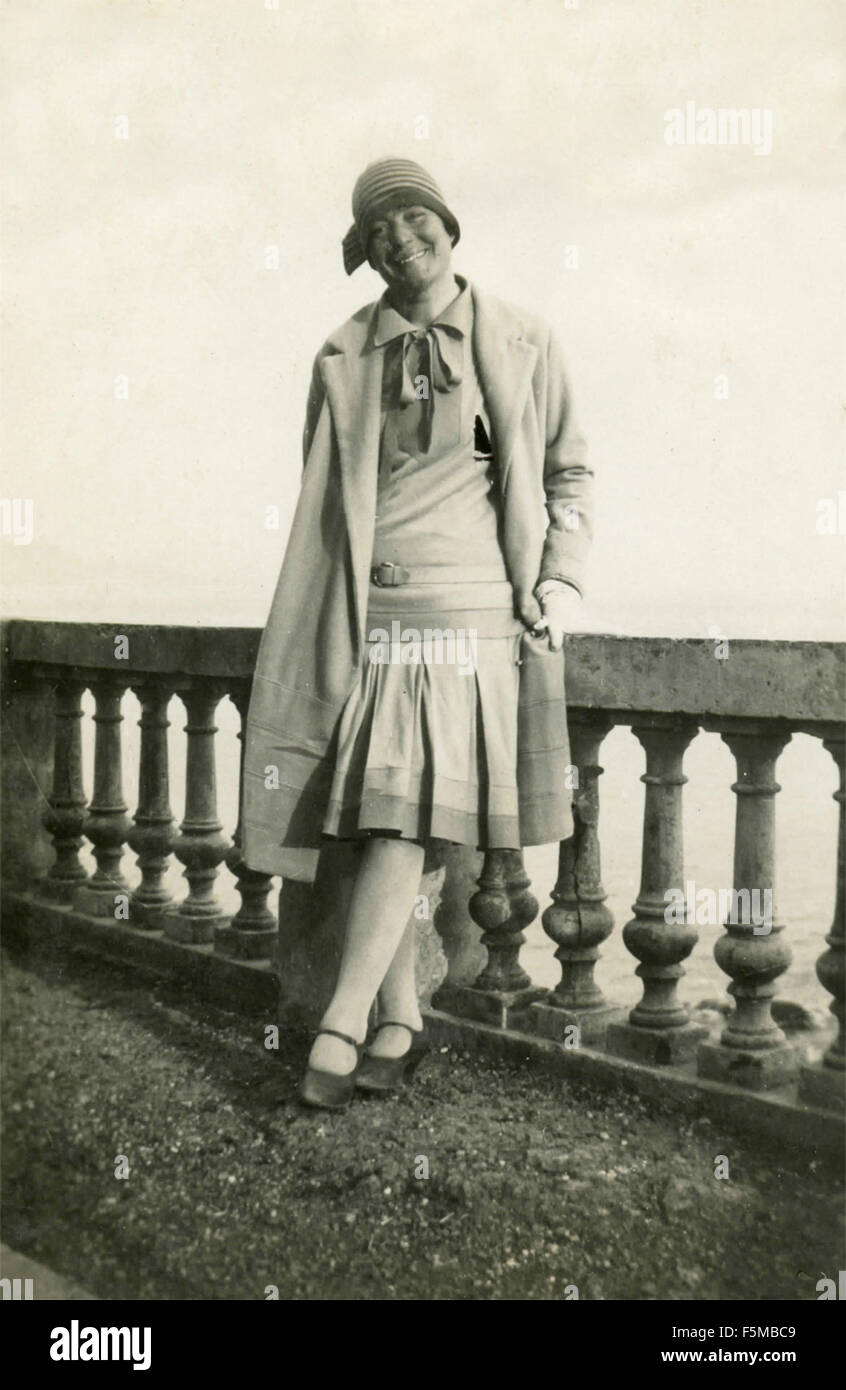 Mujer con vestido, abrigo y el sombrero al lado de una barandilla, Italia Foto de stock