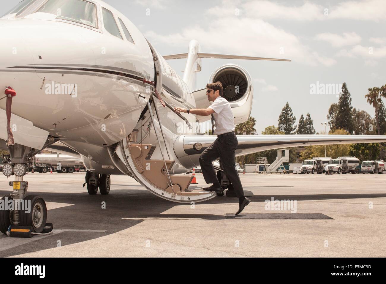 Macho piloto de jet privado subiendo a un avión en el aeropuerto Foto de stock