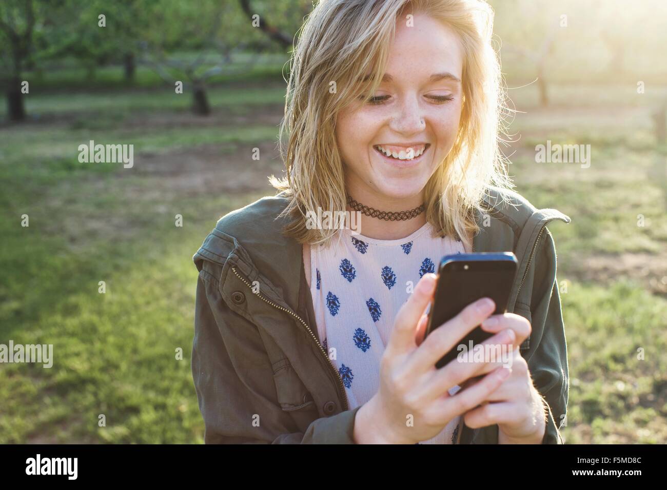 Cabeza y hombros de la mujer joven con smartphone sonriendo mirando hacia abajo Foto de stock