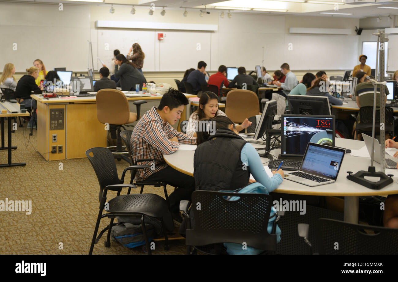 Aula con estudiantes universitarios de física trabajando sobre problemas Foto de stock