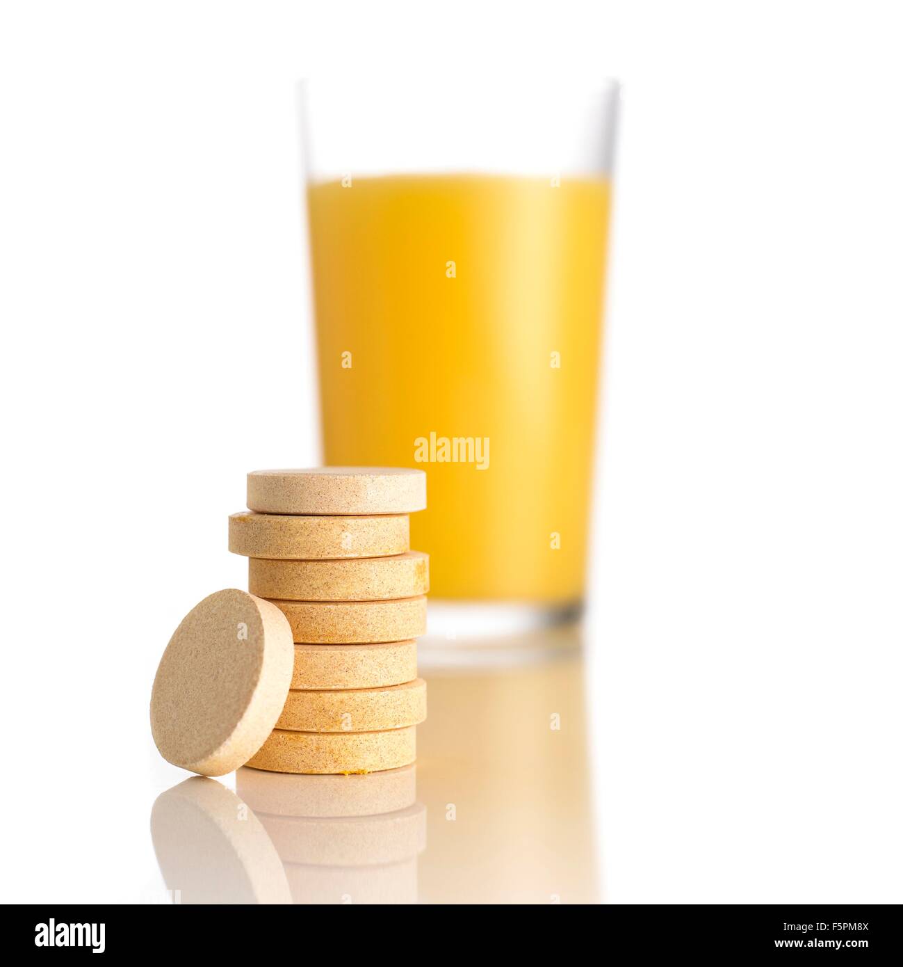 El jugo de naranja y tabletas de vitamina c contra un fondo blanco. Foto de stock