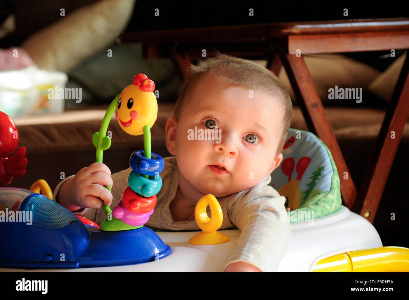 niña de 4 meses en asiento de bebé con juguetes mirando al lado del juguete  Fotografía de stock - Alamy