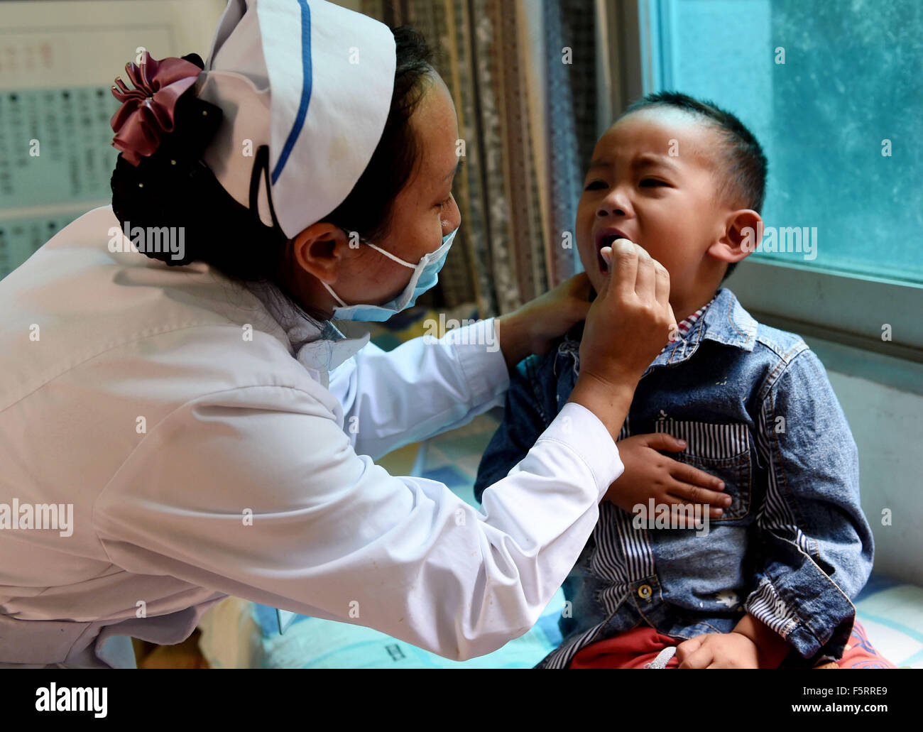 (151109) - Kunming, el 9 de noviembre, 2015 (Xinhua) -- Zhou Yifang (L), un médico de la etnia Jino, toma control médico para Li Wenbo, un niño de 3 años de etnia Jino, a un centro de salud en el municipio Jino en la ciudad de Jinghong, Prefectura Autónoma Dai de Xishuangbanna, en el suroeste de la Provincia china de Yunnan, Noviembre 4, 2015. Jino grupo étnico es una de las nacionalidades más pequeñas de China, con una población de más de 20.000 habitantes. La mayoría de las personas que viven en la zona montañosa del municipio Jino en el suroeste de la Provincia china de Yunnan. En 2014, los ingresos netos per cápita de pueblo Jino en el municipio ha aumentado a 9,308 yuan (1, Foto de stock