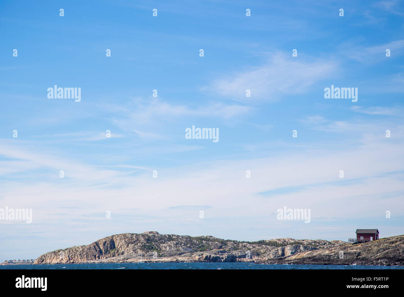 Suecia, Costa oeste, Bohuslan, Stora Dyron, orilla rocosa con casa bajo un cielo azul Foto de stock