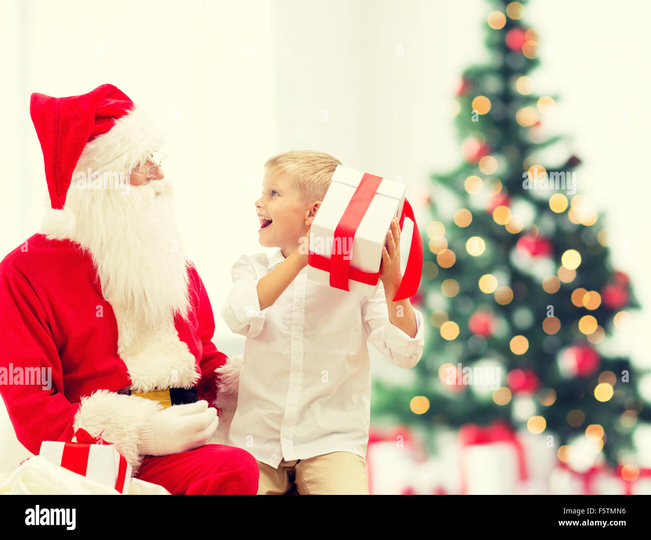 Niñito sonriente, con santa claus y regalos Foto de stock