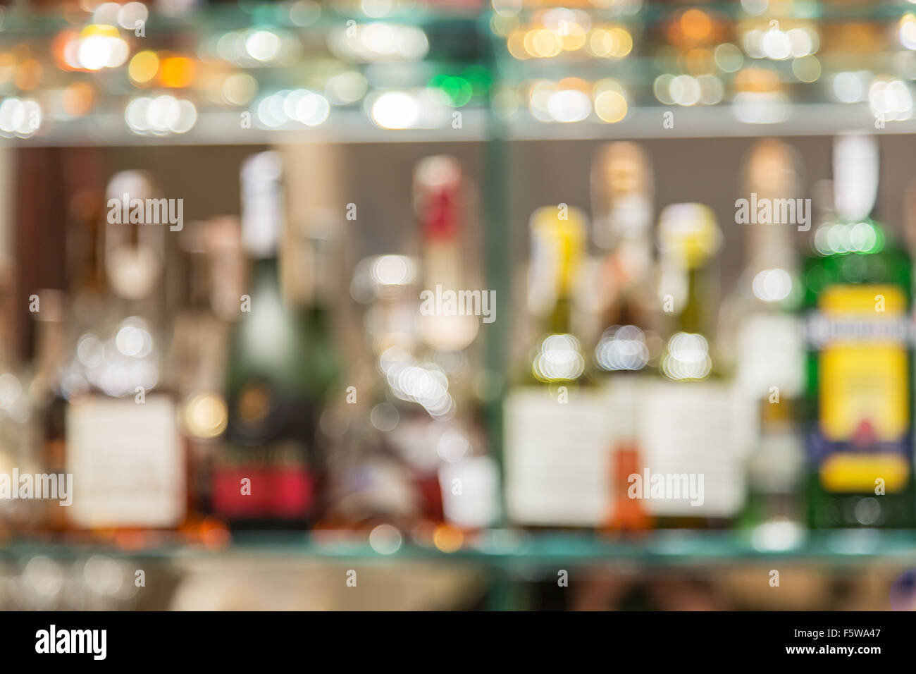 Contador de barra de cristal con estantes borrosa con botellas de alcohol en el fondo. Foto de stock
