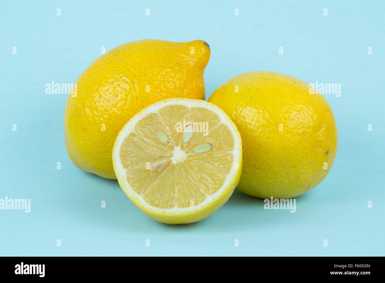 Un montón de limones sobre un fondo azul pálido. Foto de stock