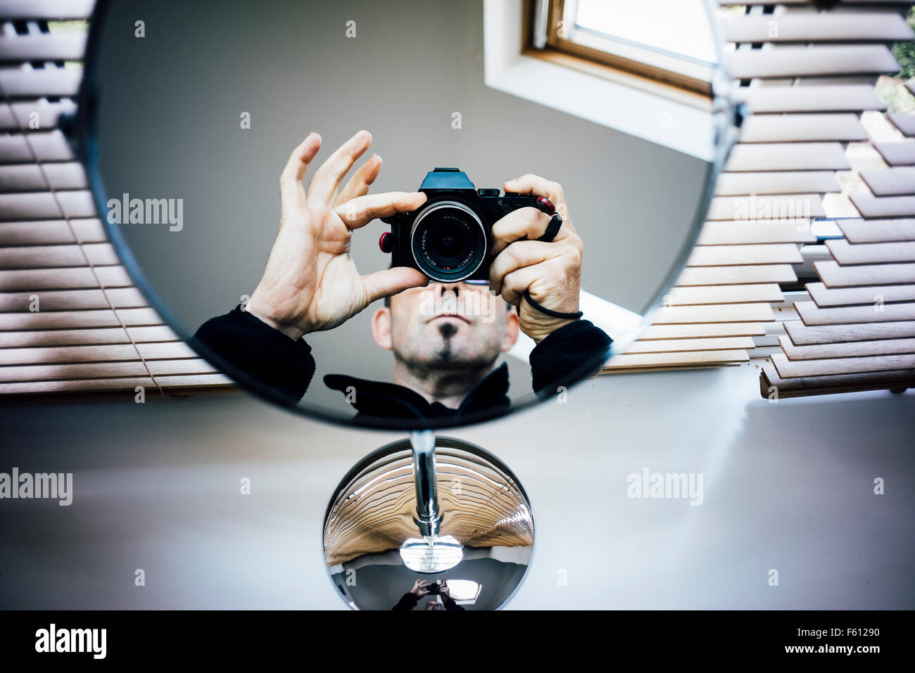 Un fotógrafo apuntando con su cámara a un espejo Foto de stock