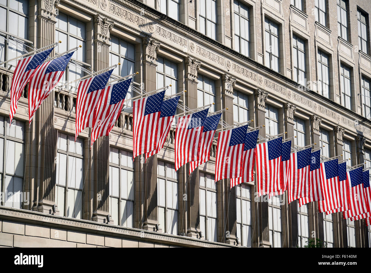 Fila de banderas americanas en un impresionante edificio en el centro de Nueva York. Foto de stock