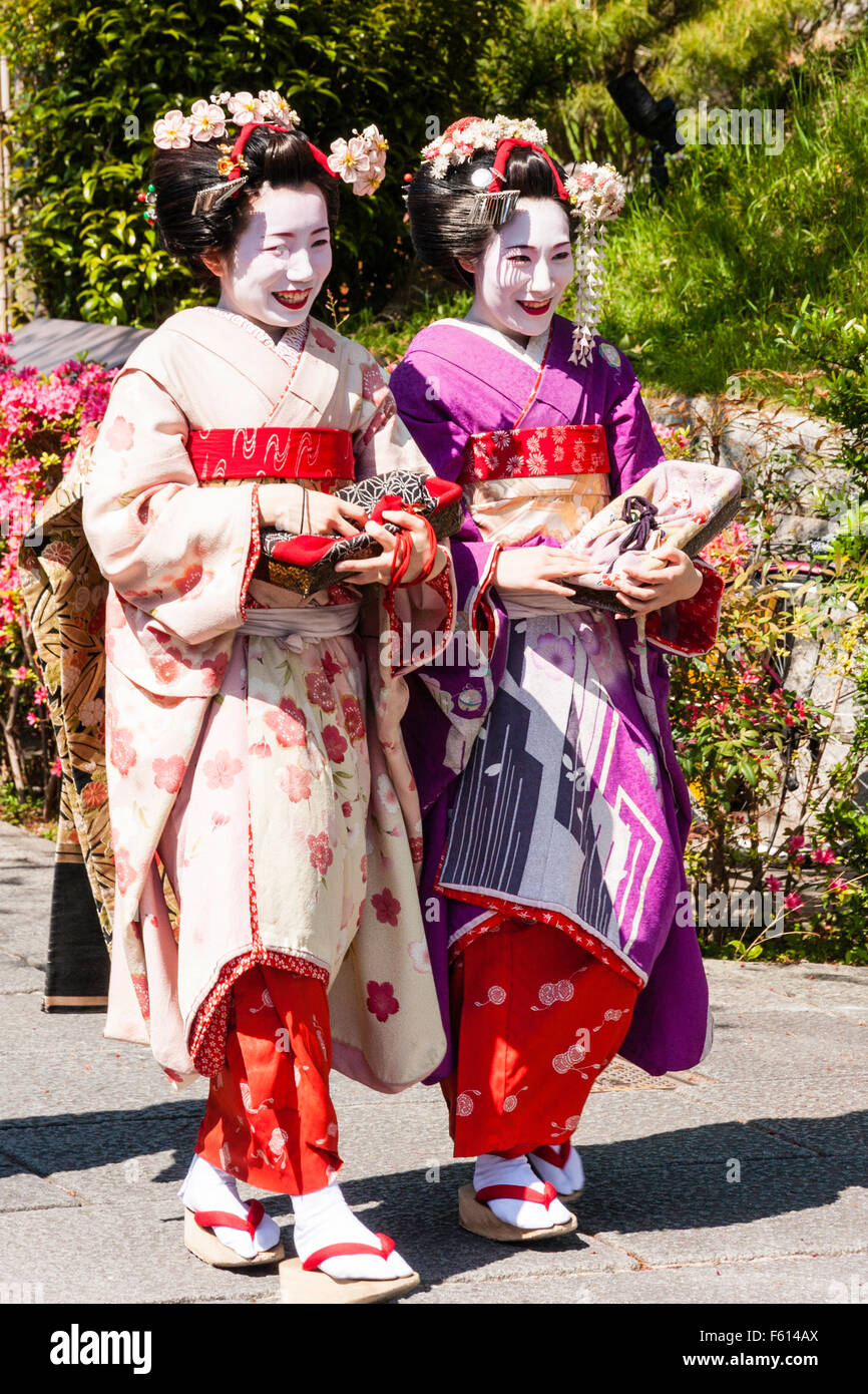 Japón (históricos, de la realeza y más) nombres Carlos Ignacio Amantini De Matteis 5 Japón, Kioto. Dos geishas maduras, kimono, Maiko, sonriendo mientras caminan a lo largo de calle en el sol de primavera. Una rosa y un kimono de color malva Fotografía de stock -