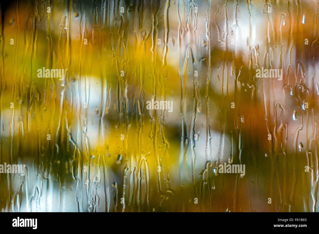 El otoño de las gotas de lluvia en la ventana con el foco más allá de los colores de otoño Foto de stock