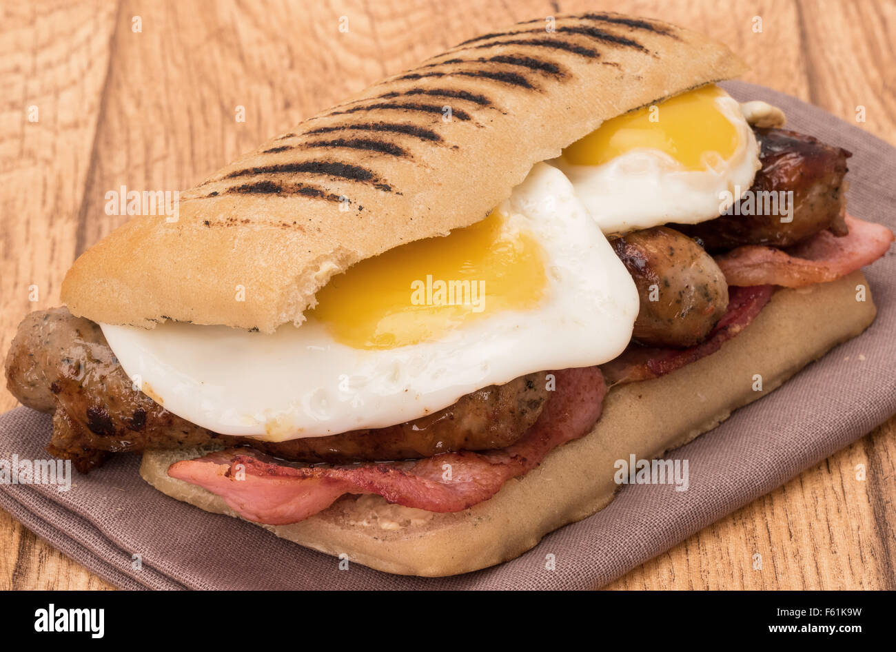 Panini desayuno con bacon, salchichas y huevos fritos Foto de stock