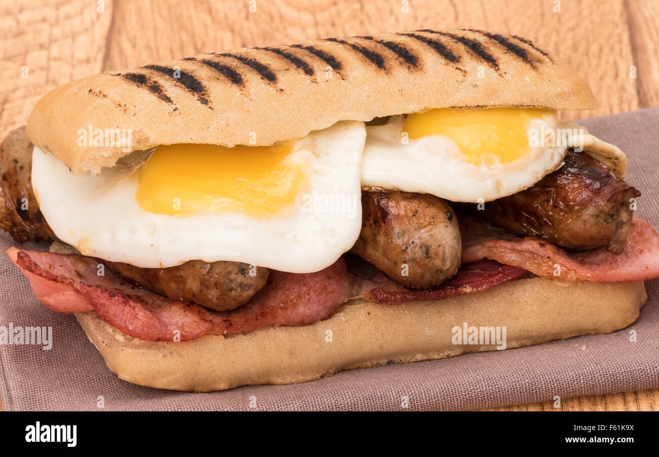 Un desayuno panini con beicon, salchichas y huevos fritos Foto de stock