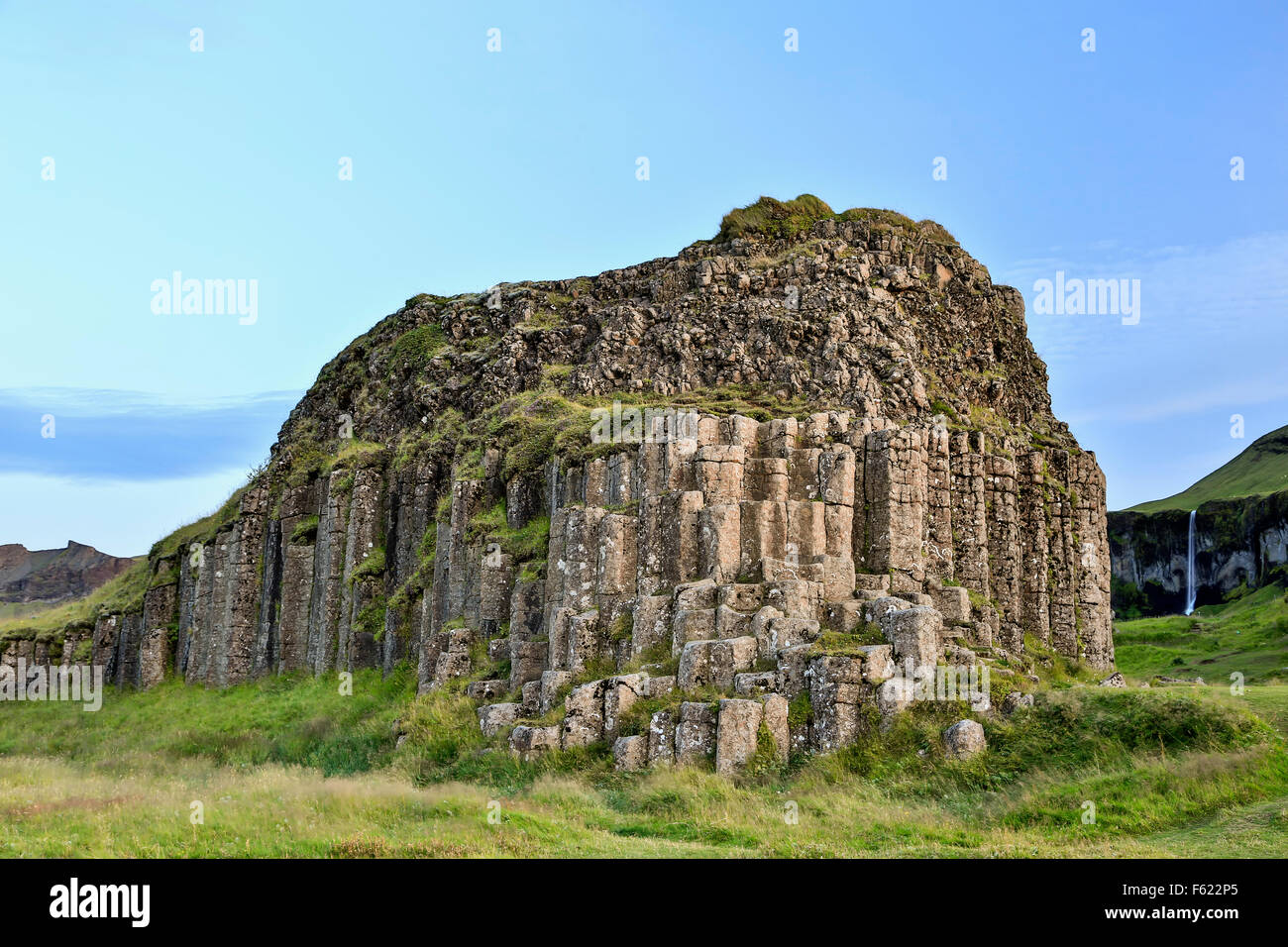 Afloramiento de basalto Columnar (y cascada en el fondo), Dverghamrar enano (acantilados), cerca de Foss, Islandia Foto de stock