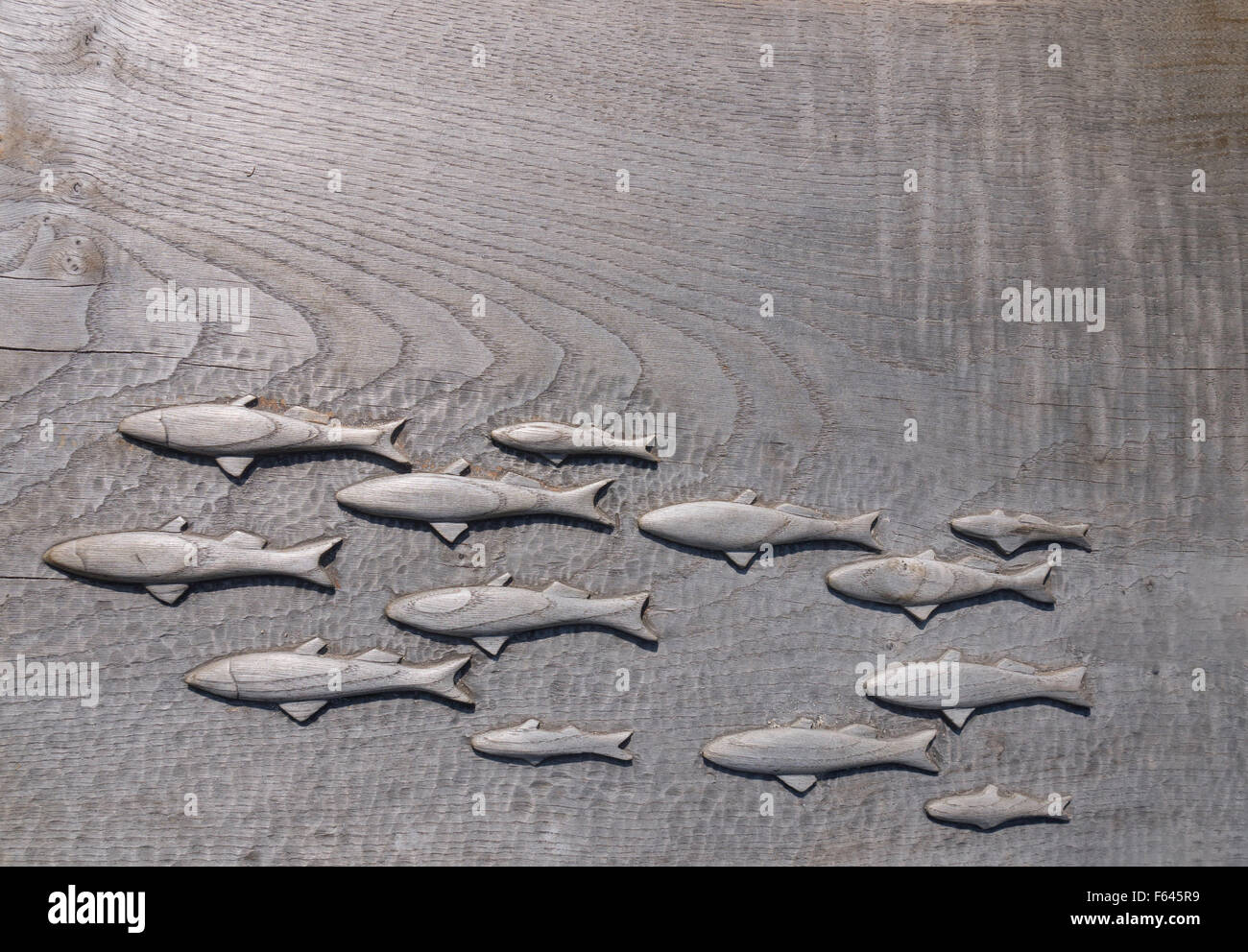 Pequeño cardumen de peces nadando - detalle tallado de madera Foto de stock