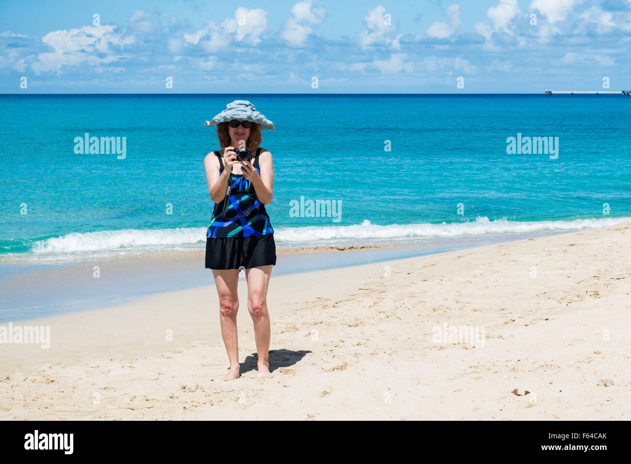 Una mujer caucásica de 50 años toma fotos en la playa de Saint Croix, Islas Vírgenes de EE.UU. Foto de stock