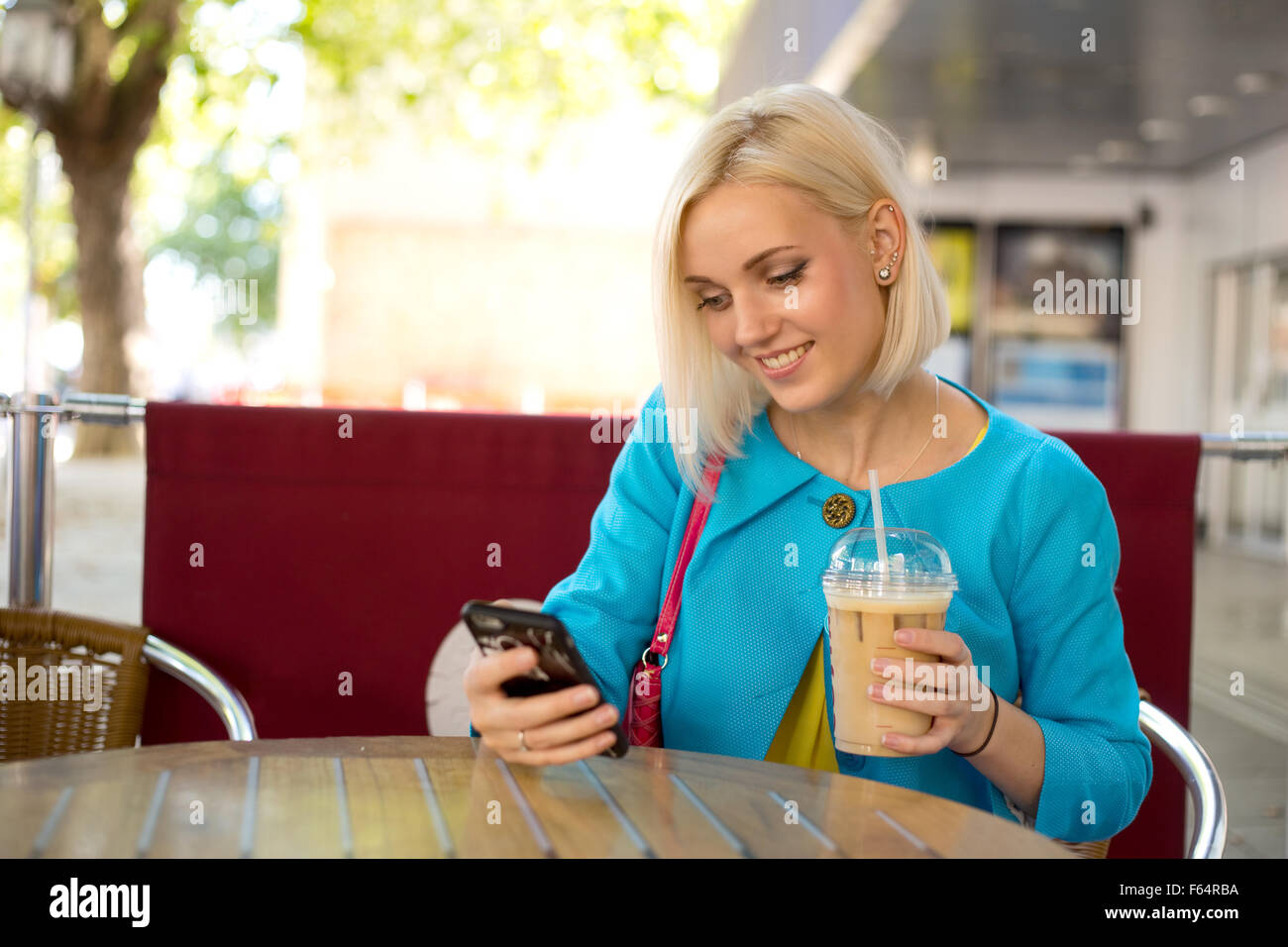 Joven Mujer colorida de revisar sus mensajes de texto en la cafetería Foto de stock