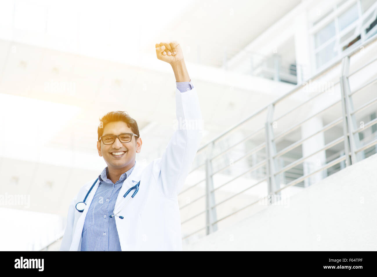 Exitoso médico indio asiático con el brazo celebrando su victoria, el edificio del hospital como fondo. Foto de stock