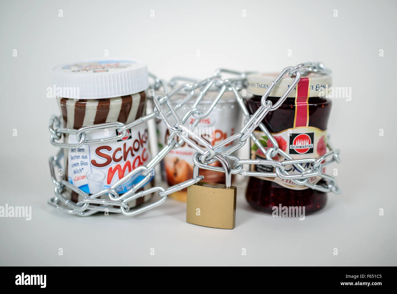 Un vaso de mermelada (derecha) y dos cremas para untar de chocolate se mantenga junto con una cadena de acero y un bloqueo, Dresde (Sajonia), Alemania, el 26 de enero de 2015. Foto: Thomas Eisenhuth Foto de stock