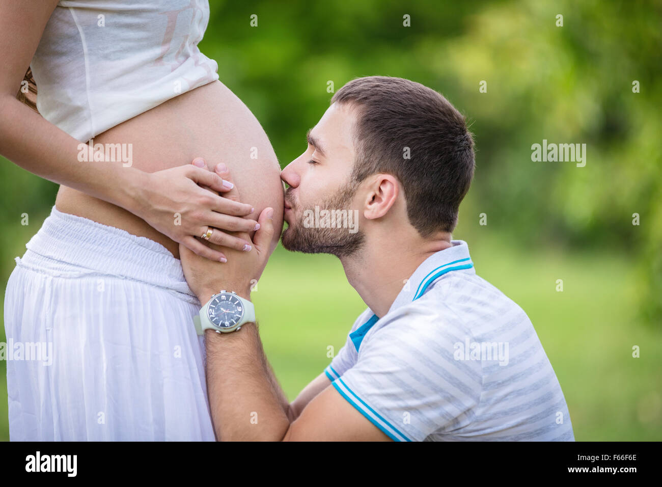 Joven besando a su esposa embarazada la barriga Foto de stock