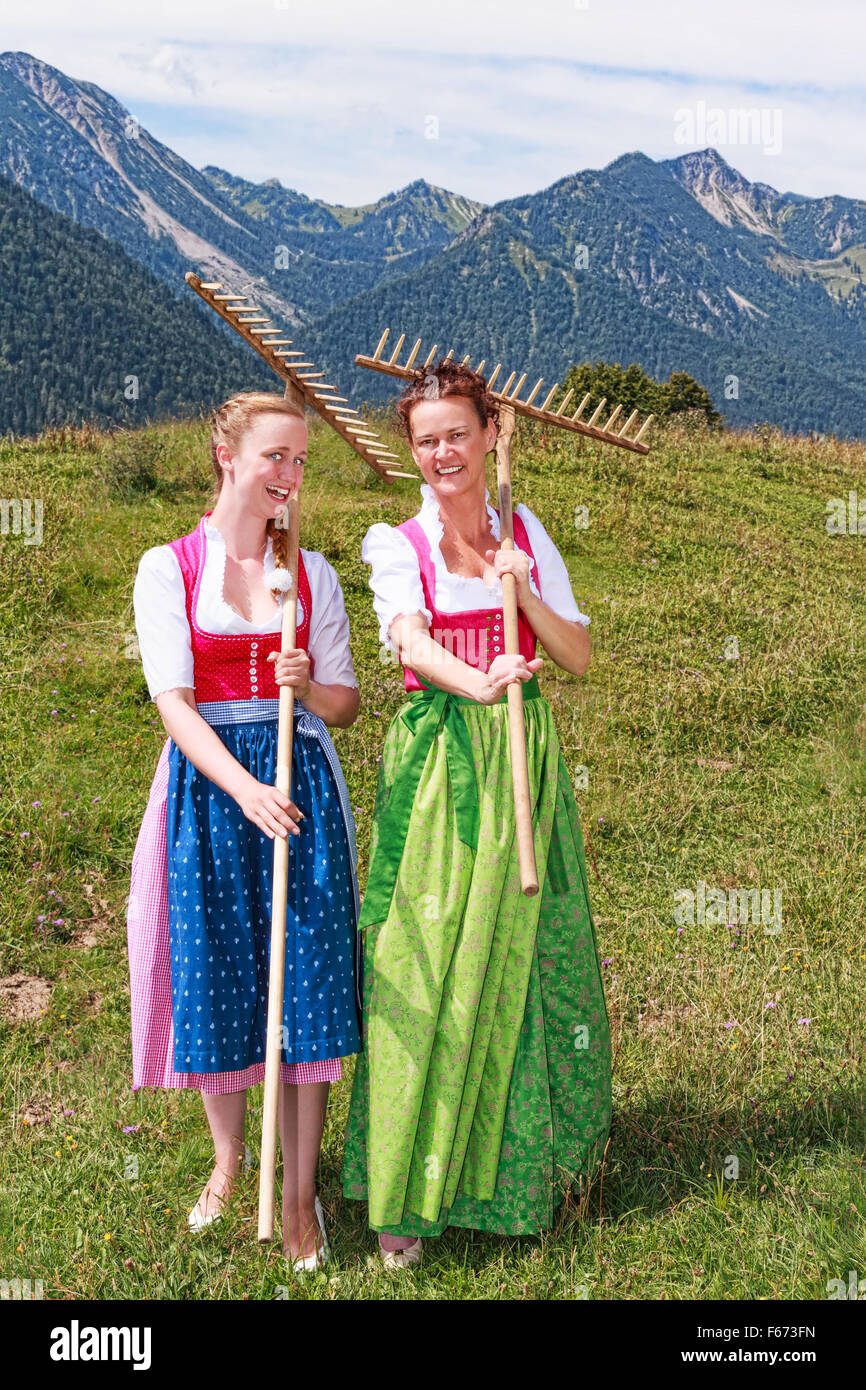 Dos mujeres dirndl con rastrillos divertirse en el trabajo Foto de stock