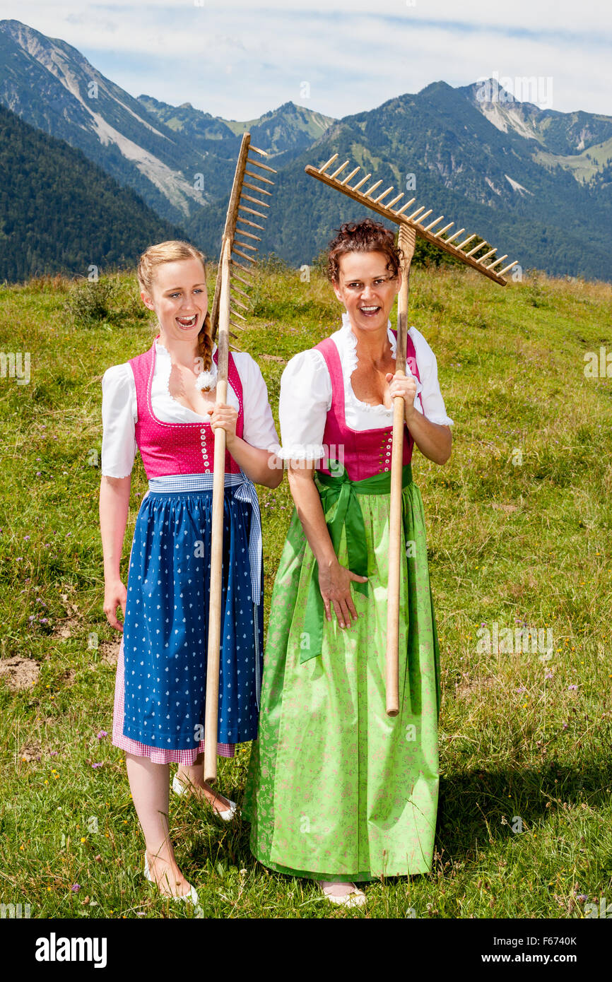 Dos mujeres dirndl con rastrillos divertirse en el trabajo Foto de stock