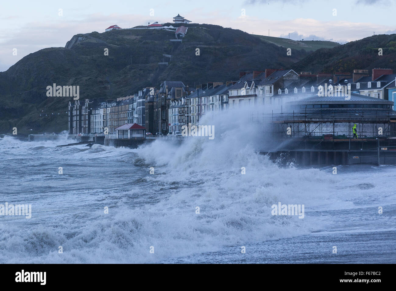 Gales Aberystwyth REINO UNIDO 13 de noviembre de 2015 Tormenta Abigail ataca a Aberystwyth esta mañana con olas furiosas mientras dos constructores intente trabajar en el andamio del nuevo quiosco en el paseo marítimo. Crédito: Ian Jones/Alamy Live News Foto de stock