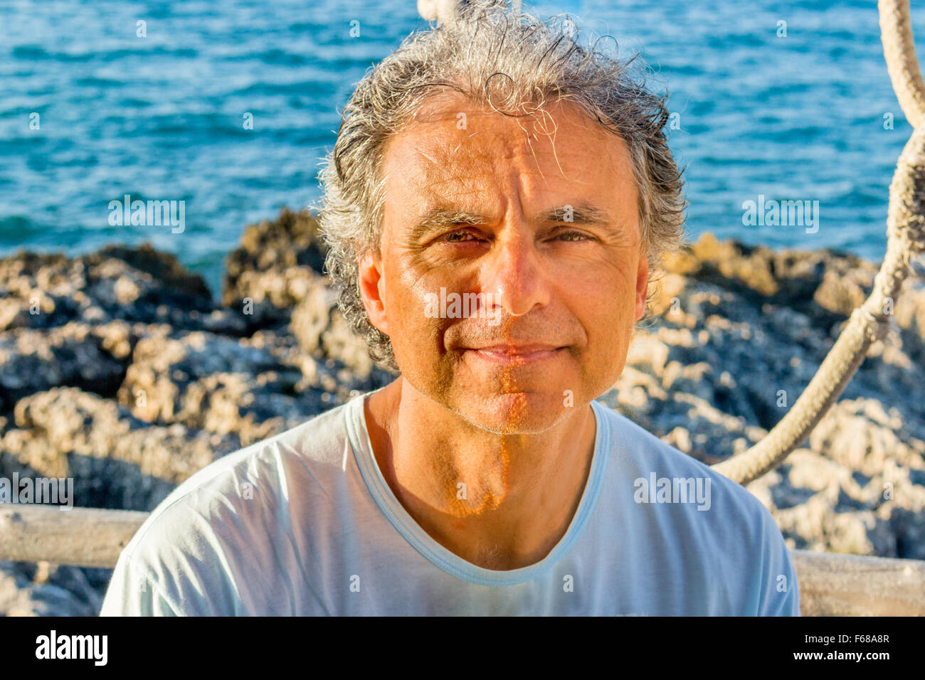 En adultos de mediana edad con una barba de tres días y t-shirt a la orilla del mar Foto de stock