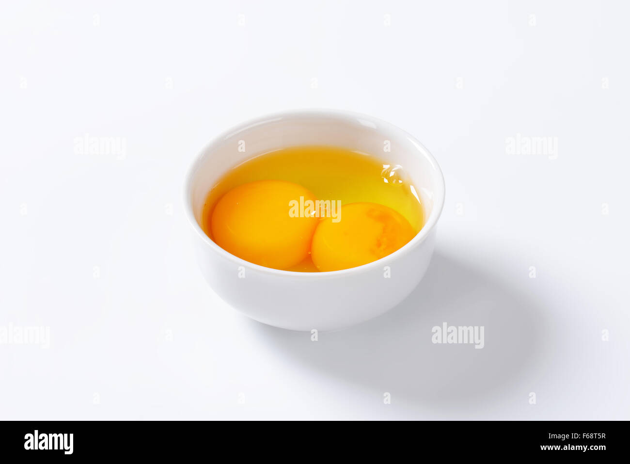 Y yemas de huevo fresco en tazón blanco Foto de stock