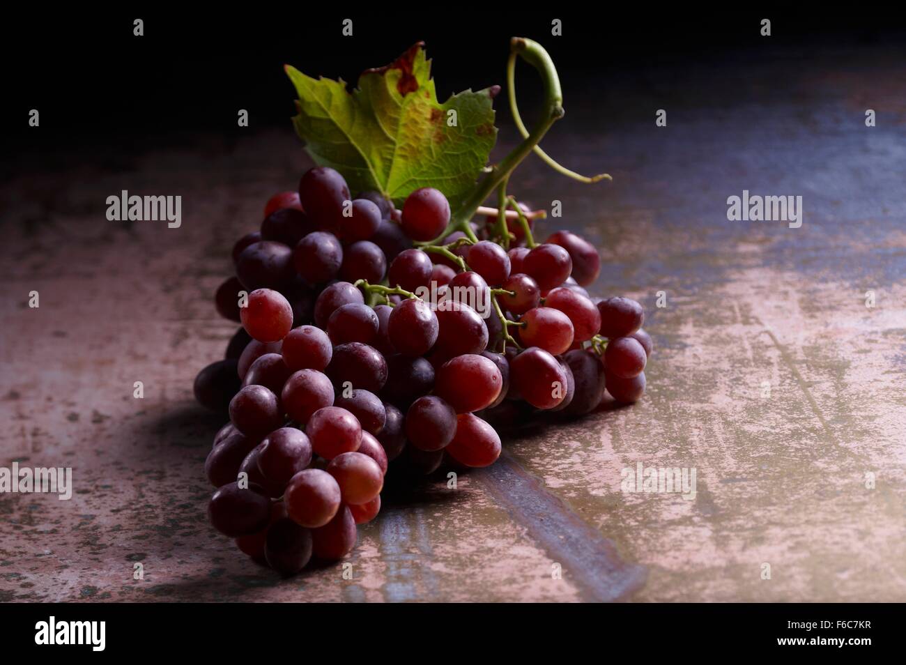 Las uvas rojas con hojas de vid Foto de stock