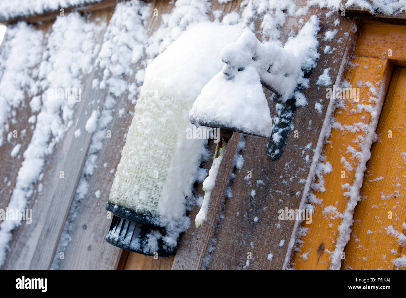 La acumulación de nieve y hielo en la puerta de una antigua campana y una más moderna la luz exterior Foto de stock