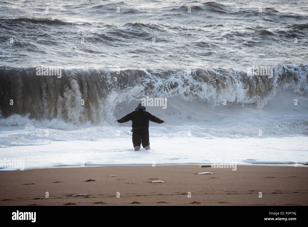 Playa de la colmena, Burton Bradstock, Dorset, Reino Unido. 18 de noviembre de 2015. Vista de una emoción en busca de hombre que caminó hacia el mar en la playa de la Colmena, Burton Bradstock para obtener una vista de cerca de las tormentosas olas rompiendo en la playa, poniendo en peligro su vida. La playa de Burton Bradstock es particularmente peligroso debido a la estantería de la playa sobre la línea de surf. Imagen: Crédito: Graham Hunt/Alamy Live News. Foto de stock